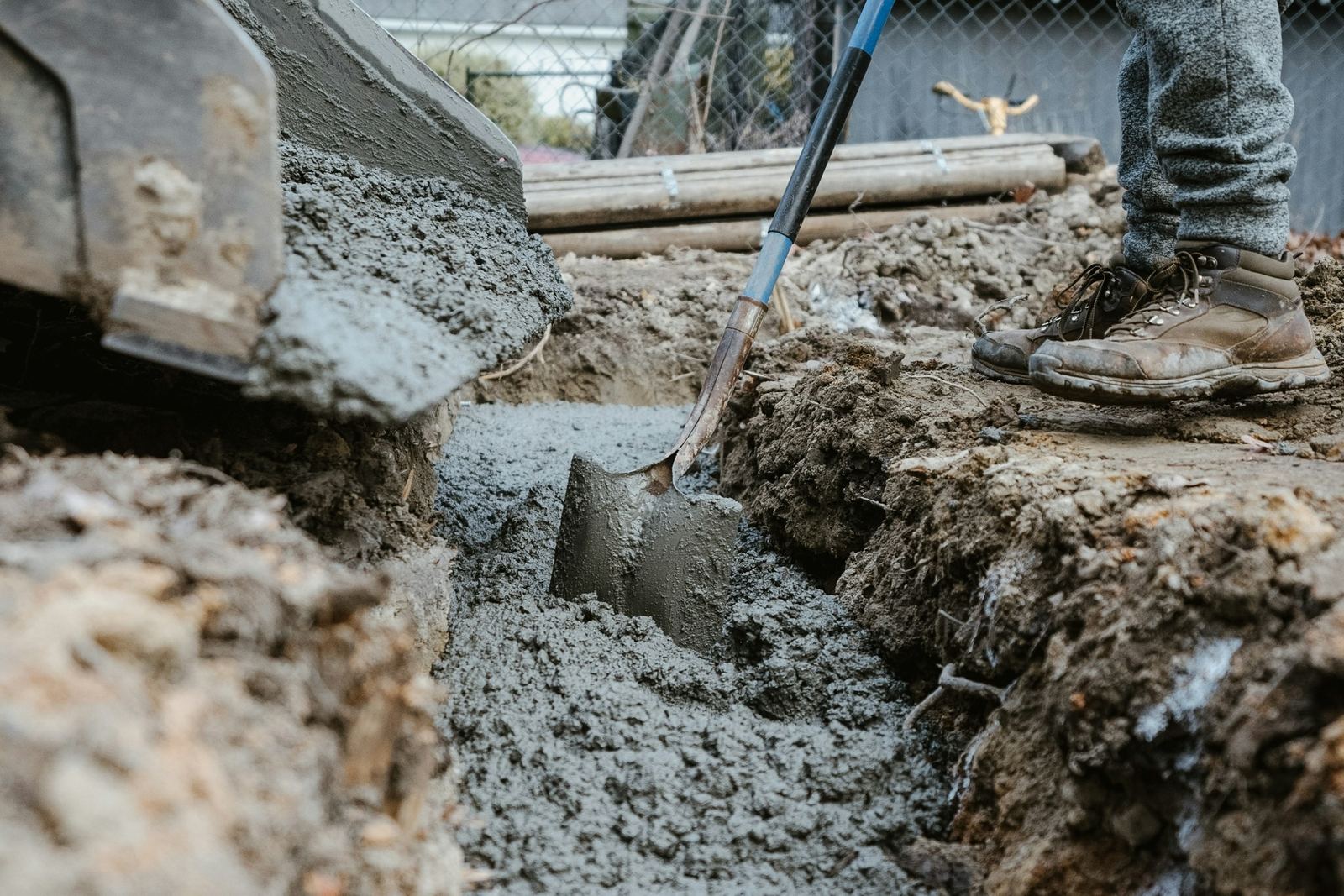 Wet concrete being placed in a footing trench beside a house