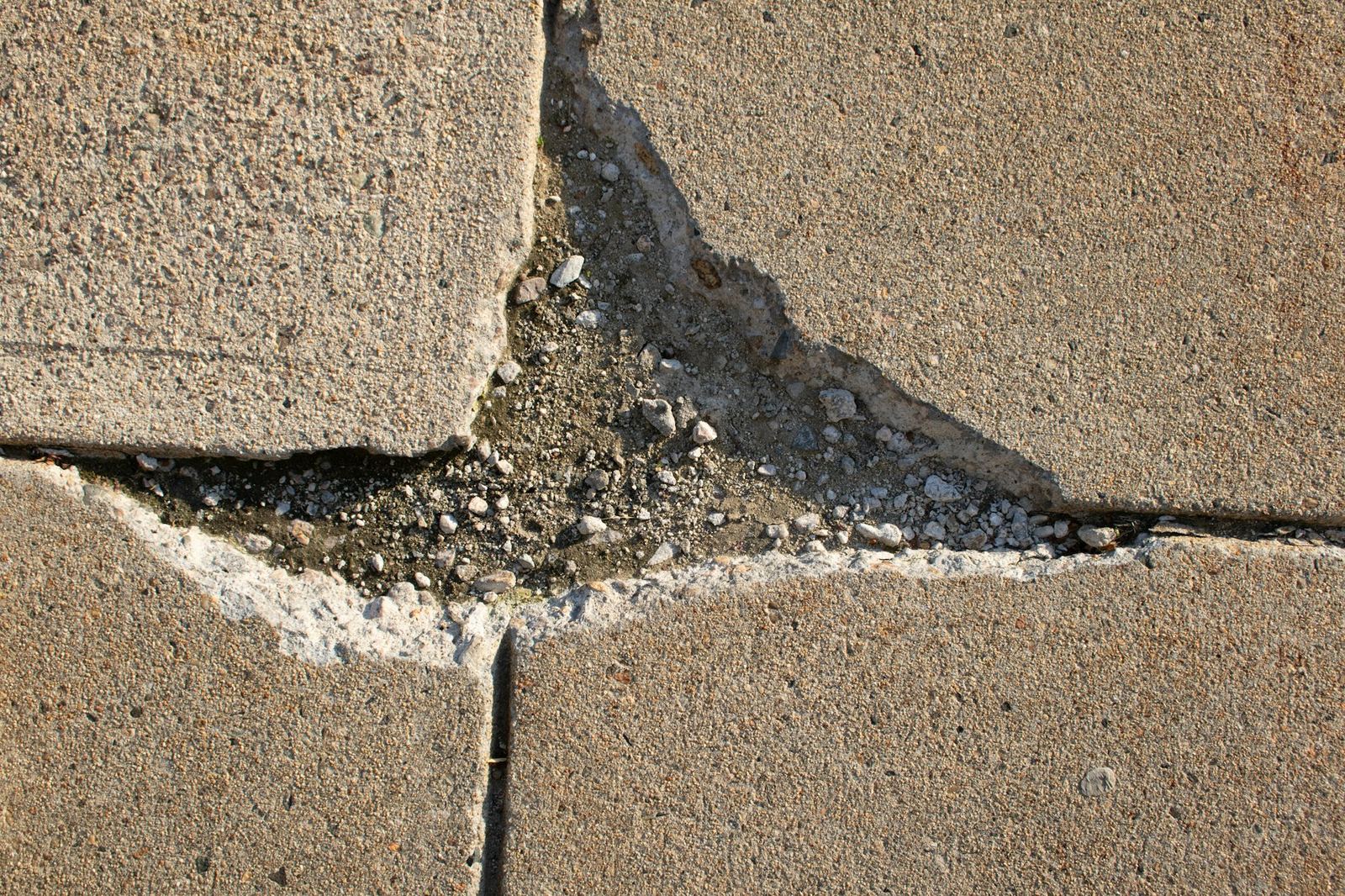 A cracked concrete slab with uneven, displaced sections