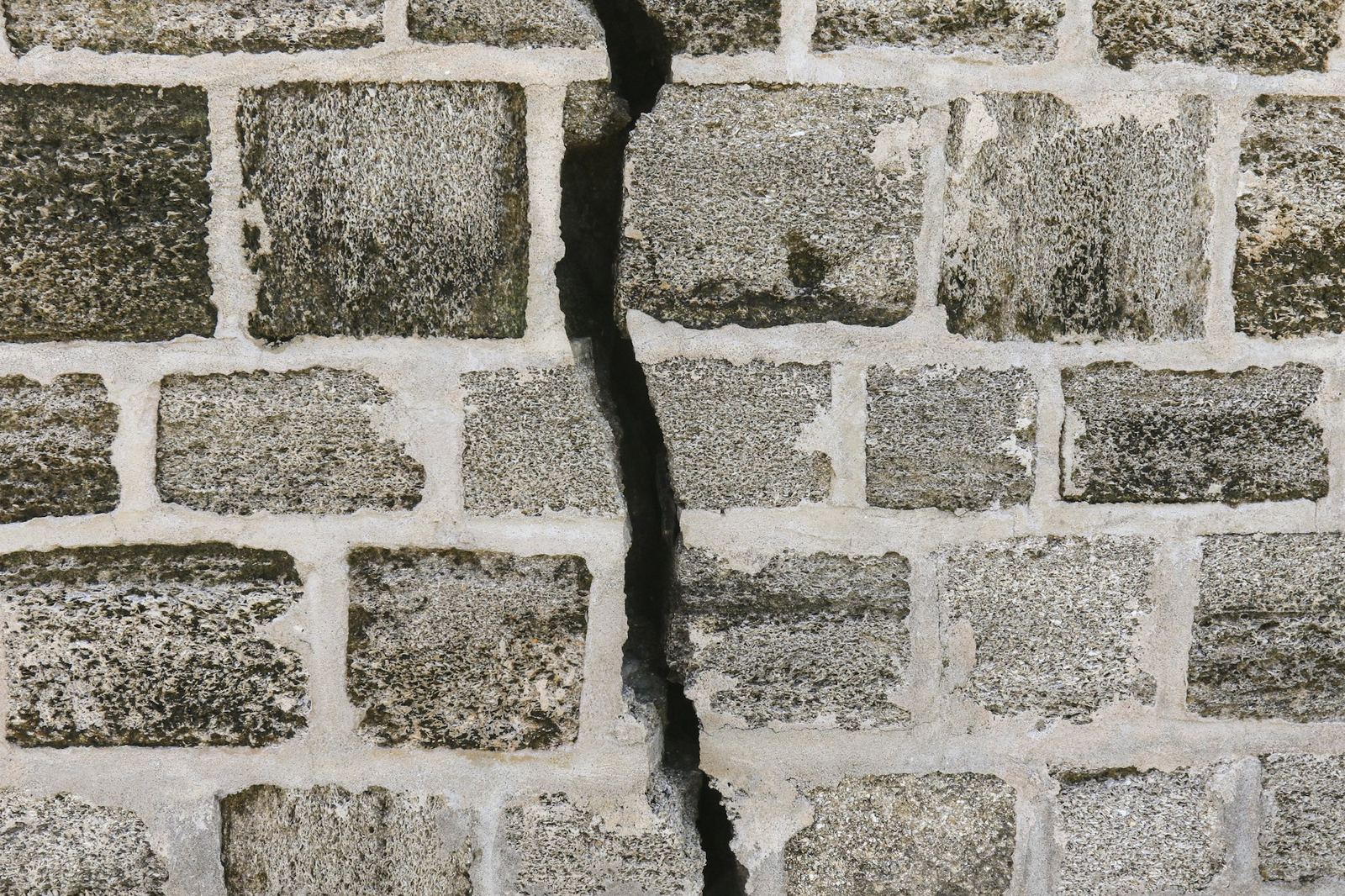A wide crack running through a concrete block wall